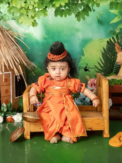 This little one dressed as Lord Ram is sitting on a small wooden bench, looking so innocent and pure.