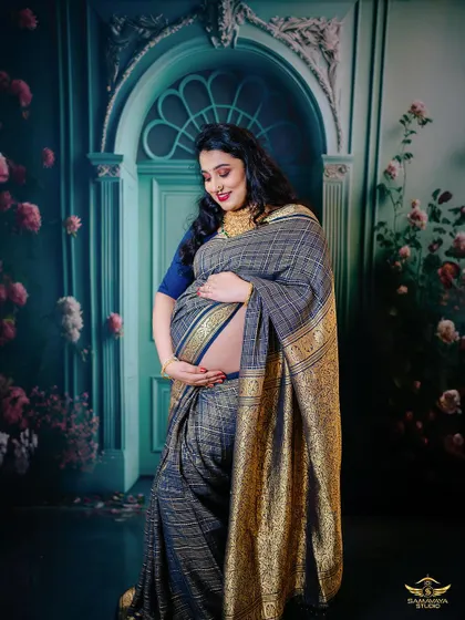 A beautiful pose showing the mother-to-be cradling her bare bump, draped in a gorgeous saree. This is a tasteful and intimate way to celebrate the female form during pregnancy.