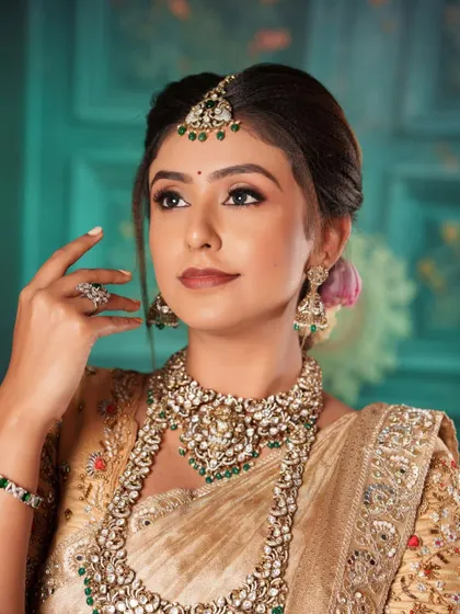 This model looks regal in a heavy choker and haara set, featuring Polki stones and green bead detailing.