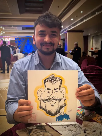 A young man proudly displays his caricature at an evening party.