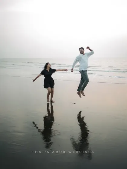 A fun, high-energy shot of a couple jumping for joy on the beach. Their reflections in the wet sand add a beautiful symmetry to this candid moment.