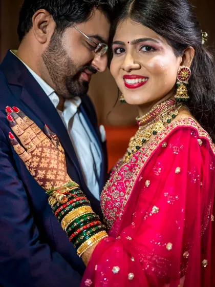 A close-up portrait focusing on the bride's happy expression and detailed mehndi, while still capturing the couple's embrace.