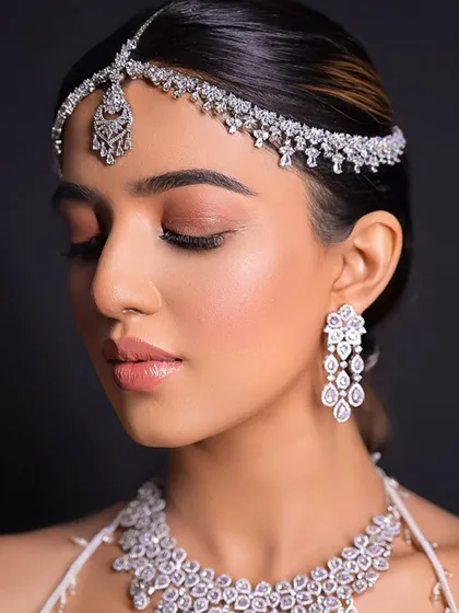 A close up on the flawless bridal glam. The hair is styled to perfectly frame the face and highlight the stunning diamond headpiece.