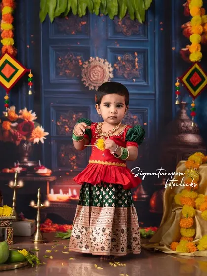 A playful moment during a traditional photoshoot. This image captures the child's personality while still showcasing the beautiful ethnic attire and festive decorations.