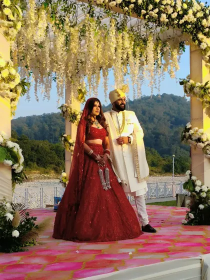 A stunning couple portrait at their riverside wedding in Jim Corbett. The mandap, adorned with cascading white wisteria, creates a dreamy backdrop against the natural landscape.