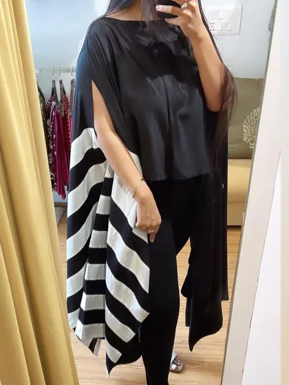 Another view of the monochrome striped cape, showing its beautiful drape and modern design. This versatile piece can be styled in many ways to create a unique and fashionable look.