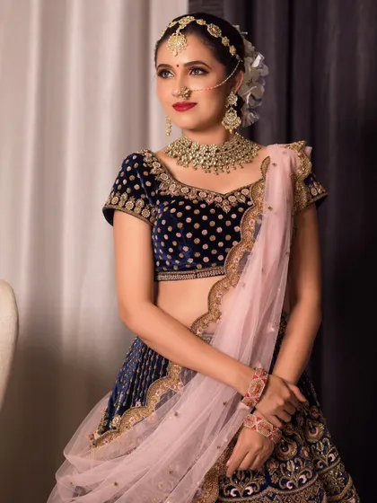 This Kundan jewelry set is perfect for a royal-themed event. The set includes a statement choker, long earrings, and a delicate matha patti, paired here with a navy blue velvet lehenga for a rich, elegant look.