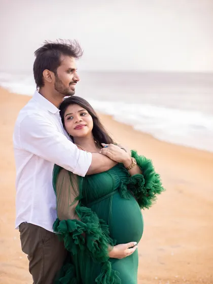 A classic couple's pose, looking out towards the future together. The serene beach setting adds to the peaceful and hopeful mood.