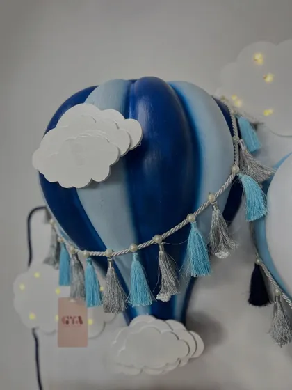A detailed shot of the handcrafted blue hot air balloon lamp with tassel accents.