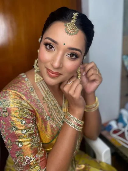 A candid moment showing the 'less is pure elegance' philosophy. The makeup is soft and bronzed, complementing the rich silk saree.