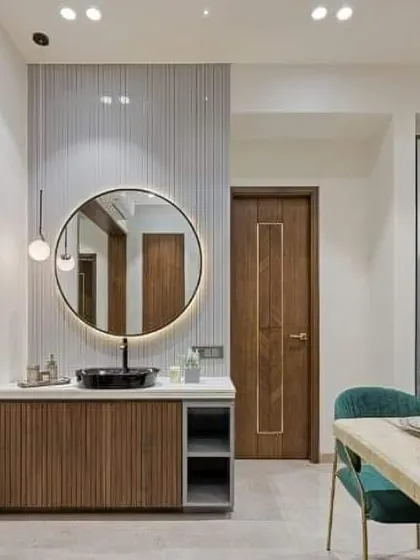A simple and chic wash basin area with a round backlit mirror and a fluted wood vanity. This design could work beautifully in a dining area or a powder room.