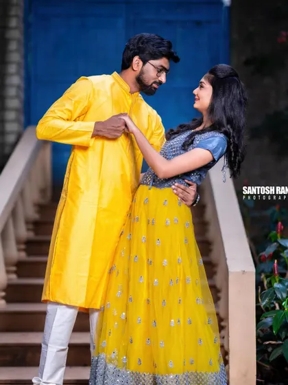 A vibrant and playful shot of a couple in contrasting yellow and blue traditional outfits.