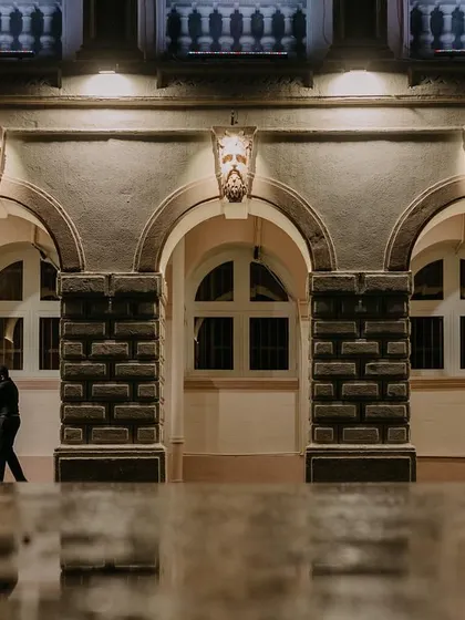 A couple embraces under the arches of a classic building, their figures reflected in the wet ground after a monsoon shower. This shot uses architectural framing and reflections to create a moody, artistic pre-wedding portrait.