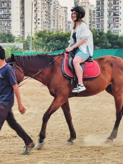 Your safety and confidence are our top priorities. This image shows a beginner rider on her first lesson, with one of our experienced trainers leading the horse to ensure a comfortable and secure introduction to riding.