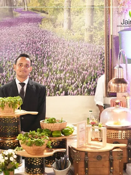 Where tradition meets taste, our dedicated Jain Caterers team is at your service. A staff member stands proudly at his well-organized station.