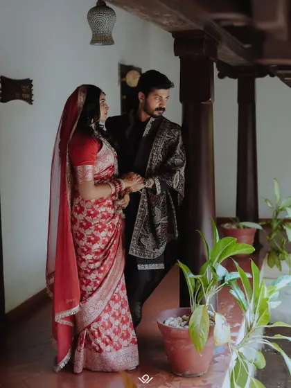 A classic, moody portrait of a couple in a traditional home, showcasing their elegant wedding attire.
