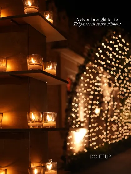 A close-up of candles in glass votives, used to line a walkway. The simple, repetitive use of candlelight creates a powerful and romantic visual path.