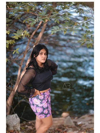 A full-length shot from the waterside series, capturing her complete look against the natural backdrop.