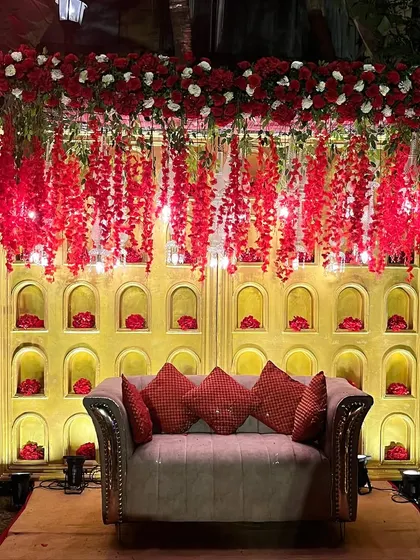 A cozy and photogenic seating spot for guests. The backdrop features a golden wall with niches, each holding a single red flower, creating a simple yet impactful photo opportunity.