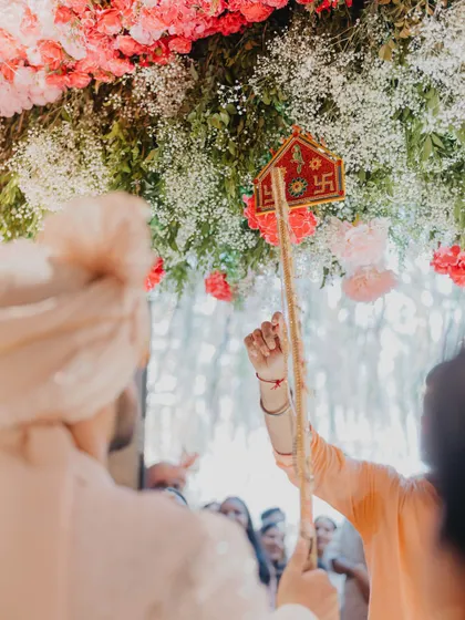 Tradition is at the heart of what we do. Here, a beautifully decorated toran, a symbolic element in Hindu weddings, is captured just before the groom's ceremonial ritual, set against a backdrop of fresh flowers.