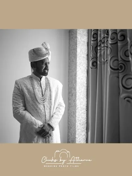 A classic black and white portrait of the groom by a window. This timeless shot captures his contemplative mood and the fine details of his wedding sherwani.
