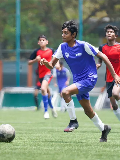 A young footballer sprints with the ball, demonstrating the speed and control we emphasize in our training programs.
