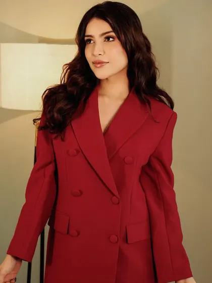 A different pose from the same shoot, highlighting the sharp tailoring of the blazer and the soft makeup.
