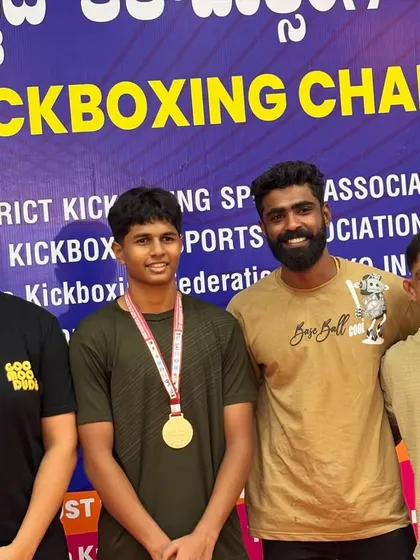 A young champion with his gold medal, standing with his coaches. We build them strong and confident from a young age.