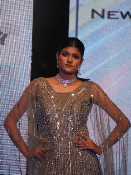 A model presents a heavily embellished gown with flowing sleeves, a testament to our students' craftsmanship.