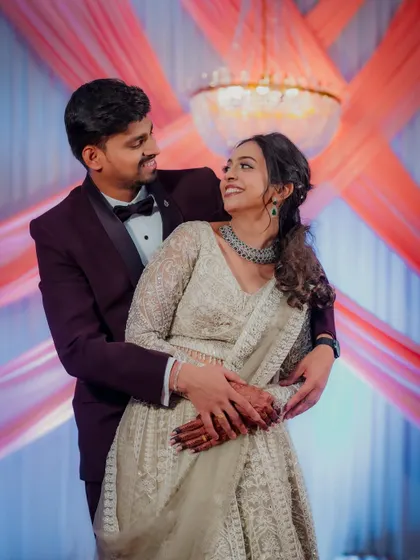 Kasturi and Nikhil share a loving gaze during their engagement shoot. The grand chandelier and elegant decor add a touch of glamour to this romantic portrait.