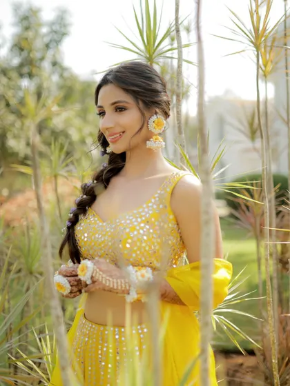 The beautiful bride enjoying a quiet moment before her Goa Haldi. Her floral jewelry perfectly complements the yellow theme.
