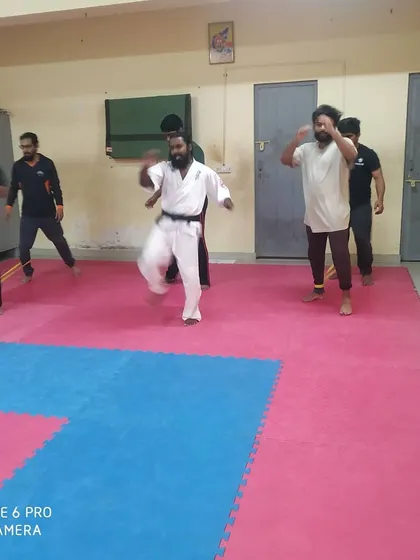 A group of students performing leg conditioning exercises together on the dojo mats.