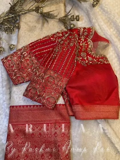 A classic red and white combination for a bride. The red blouse is heavily embroidered with zardosi work, creating a beautiful contrast with the white saree.