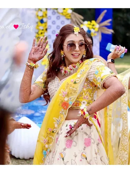 Our 'swag waali bride' Rumani, dancing at her Haldi function. She is wearing a custom-made pastel floral jewellery set, including a necklace, hathphool, and tikka.