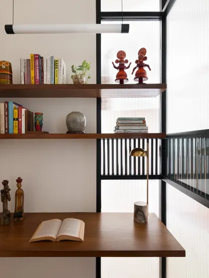 Inside the study pod, floating teak shelves provide storage for books and objects. The design is minimal and functional, creating a calm and organized workspace.