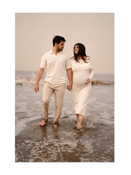 A candid shot of the couple walking and talking by the waves, showcasing a natural and relaxed beach vibe.