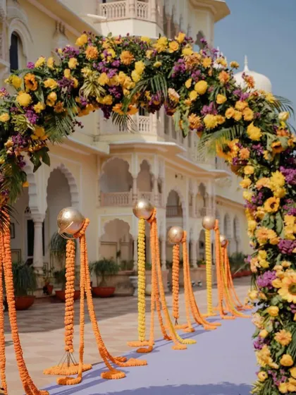 A closer view of the magnificent floral arch at the palace entrance, showcasing the dense arrangement of yellow and purple flowers.
