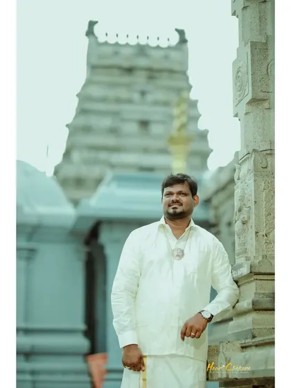 A solo portrait of the groom in traditional attire, standing proudly in front of the temple.