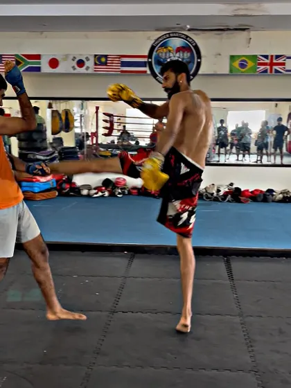 A student throws a teep (push kick) to maintain distance during sparring. This is a key element of ring control.