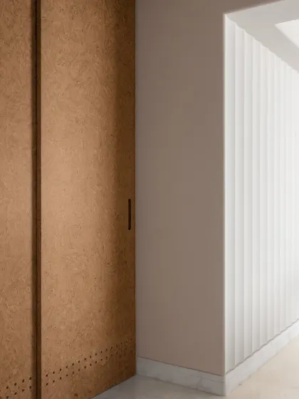 A detail of the material palette, with cork-paneled doors and fluted walls adding texture and warmth to the corridor.