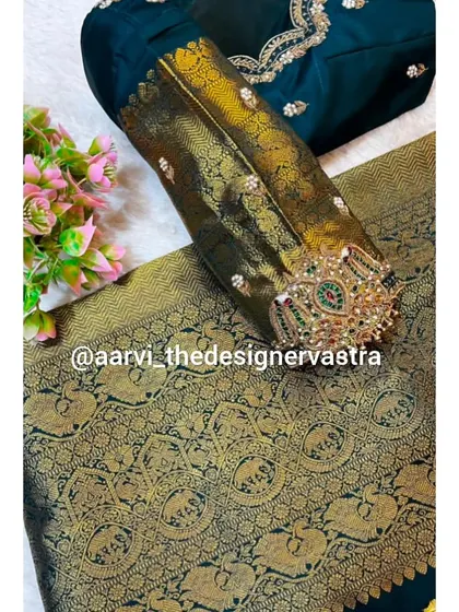 A detailed shot of the embroidered vanki design on the sleeve of the dark green blouse, a unique and traditional touch.