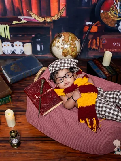 Another angle from our popular Harry Potter themed shoot. This baby, dressed in a cute plaid outfit and scarf, looks like a tiny scholar surrounded by books, candles, and magical props.