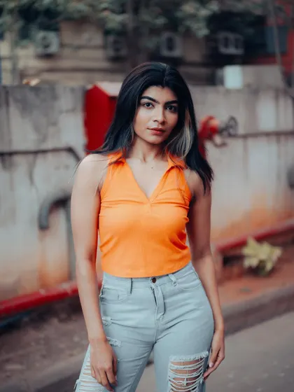 A duplicate of image 489, this portrait of a model sitting in an industrial area, with a bright orange top against red pipes, is vibrant and edgy.