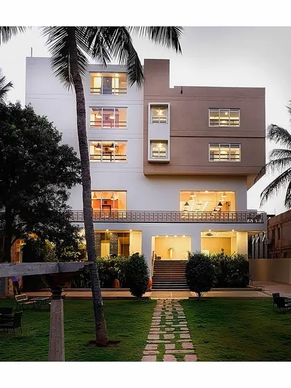 The entrance to a hotel project, featuring a beautifully landscaped garden that creates an inviting transition into the building. The design balances modern block forms with warm, open ground-floor spaces.