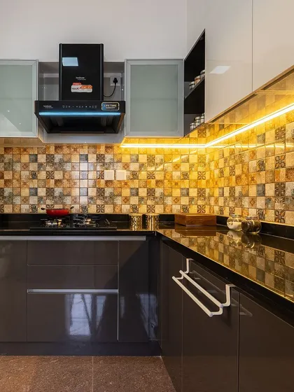 A closer look at the L-shaped kitchen, showing the warm under-cabinet lighting that illuminates the countertop and the stylish mosaic tiles.