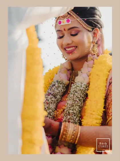 A radiant bride smiling during the ceremony. This close-up captures her happiness and the beauty of her traditional attire and floral garlands.