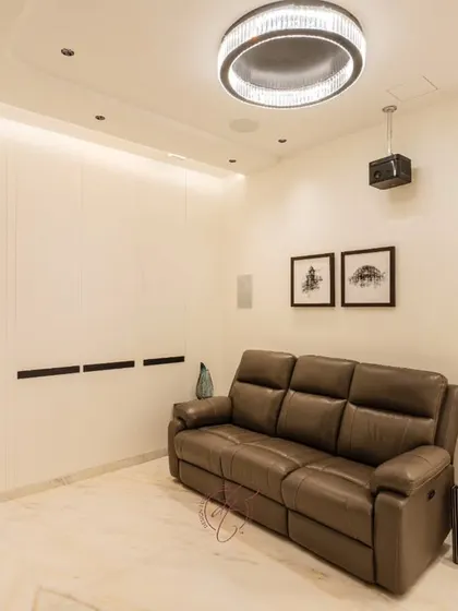 A full view of the home theater, showing the comfortable reclining sofa, the ceiling-mounted projector, and the discreetly placed surround sound speakers. Every element is designed for optimal viewing and comfort.