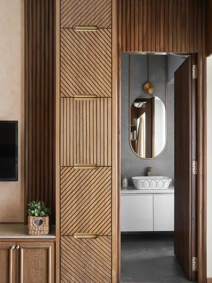 A view of the parent's bedroom, showing the custom wardrobe with its intricate wood grain and fluted patterns, leading into the ensuite bathroom.