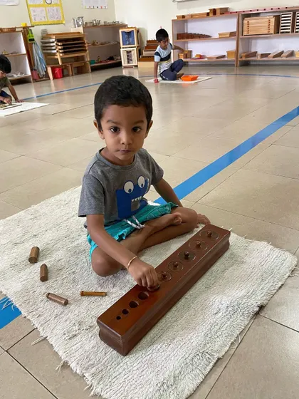 The Cylinder Blocks are a foundational sensorial material. By fitting each cylinder into its correct socket, the child refines their pincer grip for writing and develops their ability to visually discriminate between different dimensions.