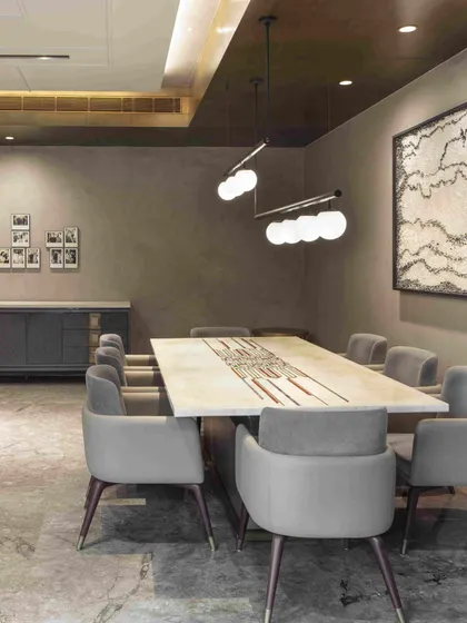A wider view of the informal dining area, showing the custom table by Furgonomics and chairs by Alsorg. The space opens onto a courtyard, allowing natural light to fill the room.